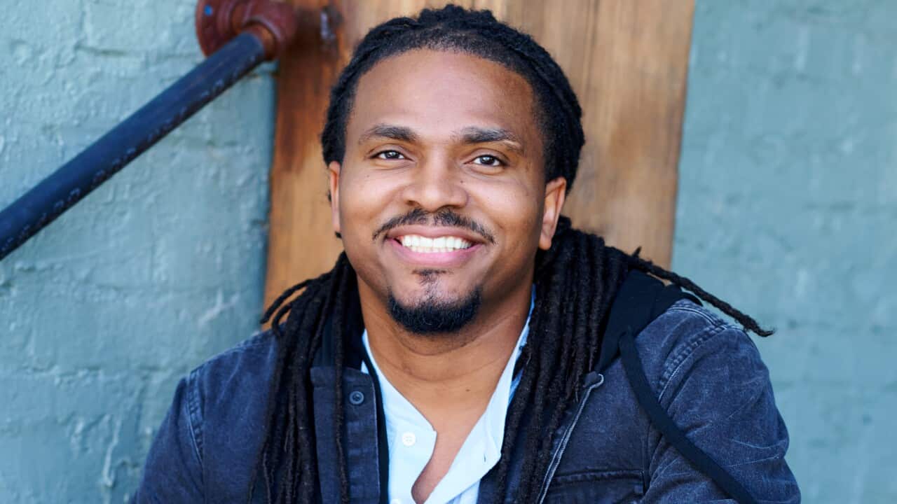 A man smiles as he sits on some steps.