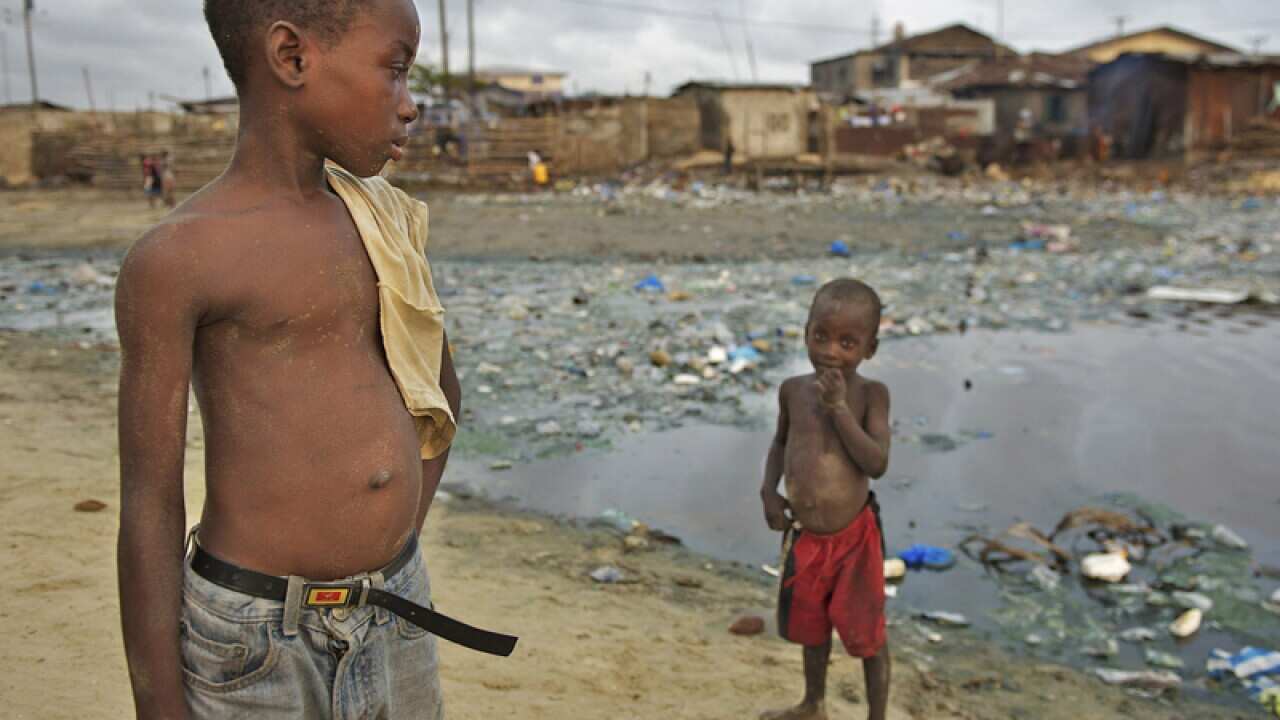 Children stand by a pool of stagnant water in Liberia