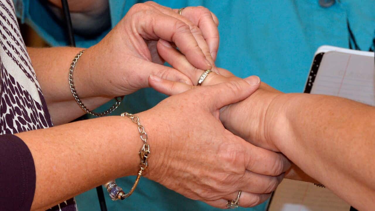 Karen Roberts, left, places a wedding band on the finger of her partner April Miller as they renew their vows in a public ceremony.