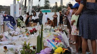 People line up and place flowers at a memorial to victims of the Bondi terror attack