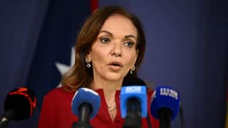 Federal Minister for Multicultural Affairs Anne Aly speaks in front of a podium.