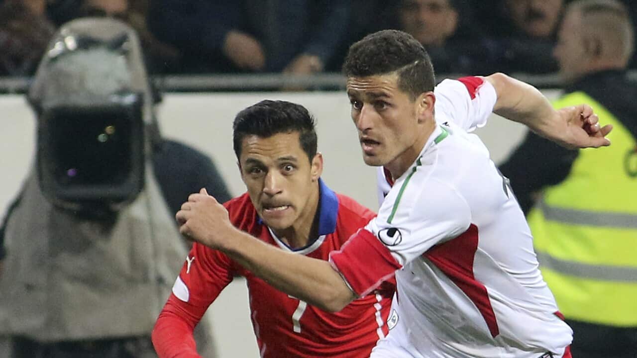 Two men playing football, one with the ball and the other is close pursuit.