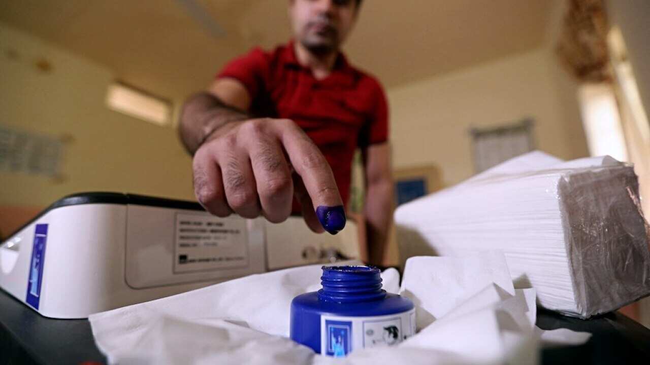 An Iraq man inks his finger after casting his ballot