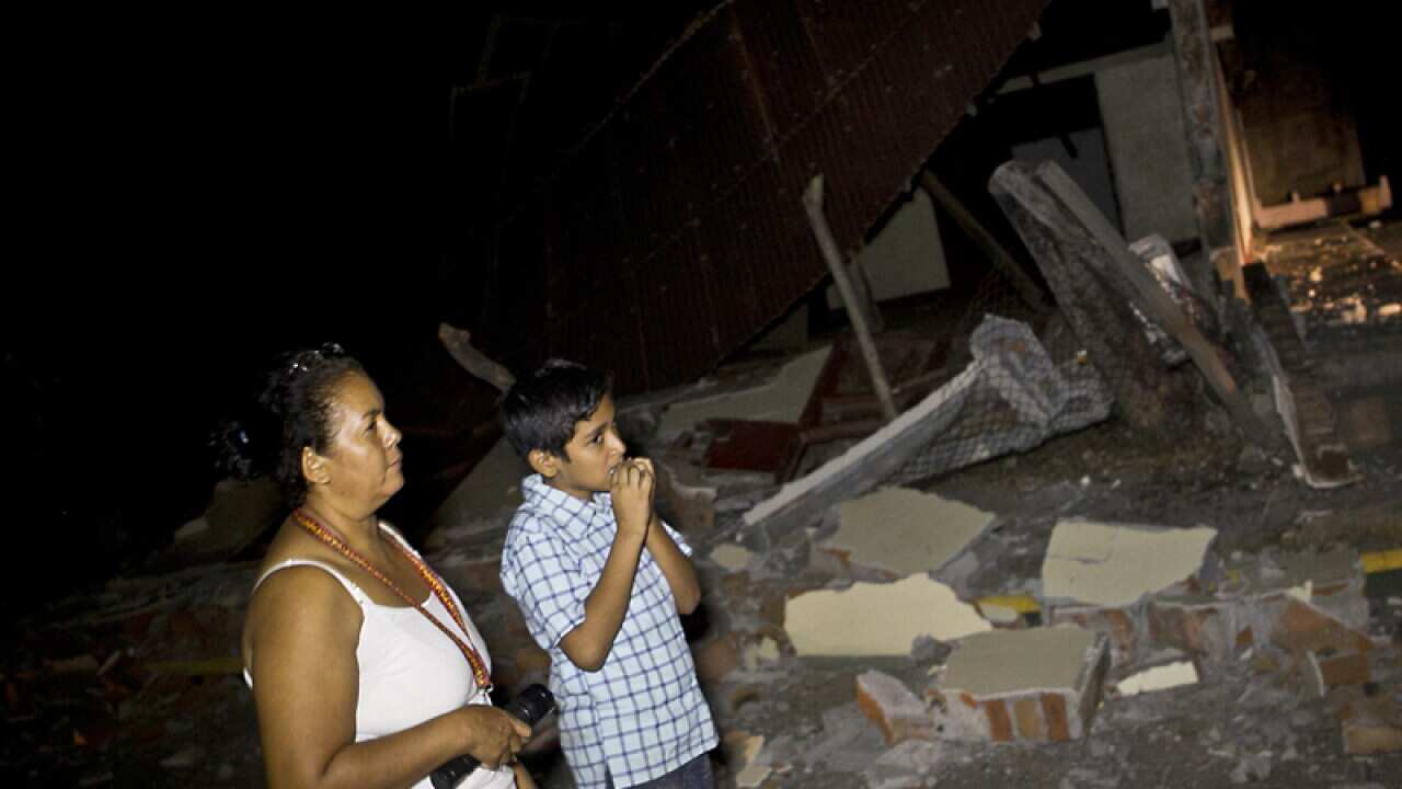 A woman and a boy stand near a destroyed home
