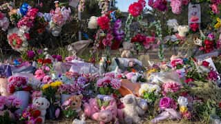 A wire fence covered in flowers and soft toys paying tribute to Kumanjayi Little Baby