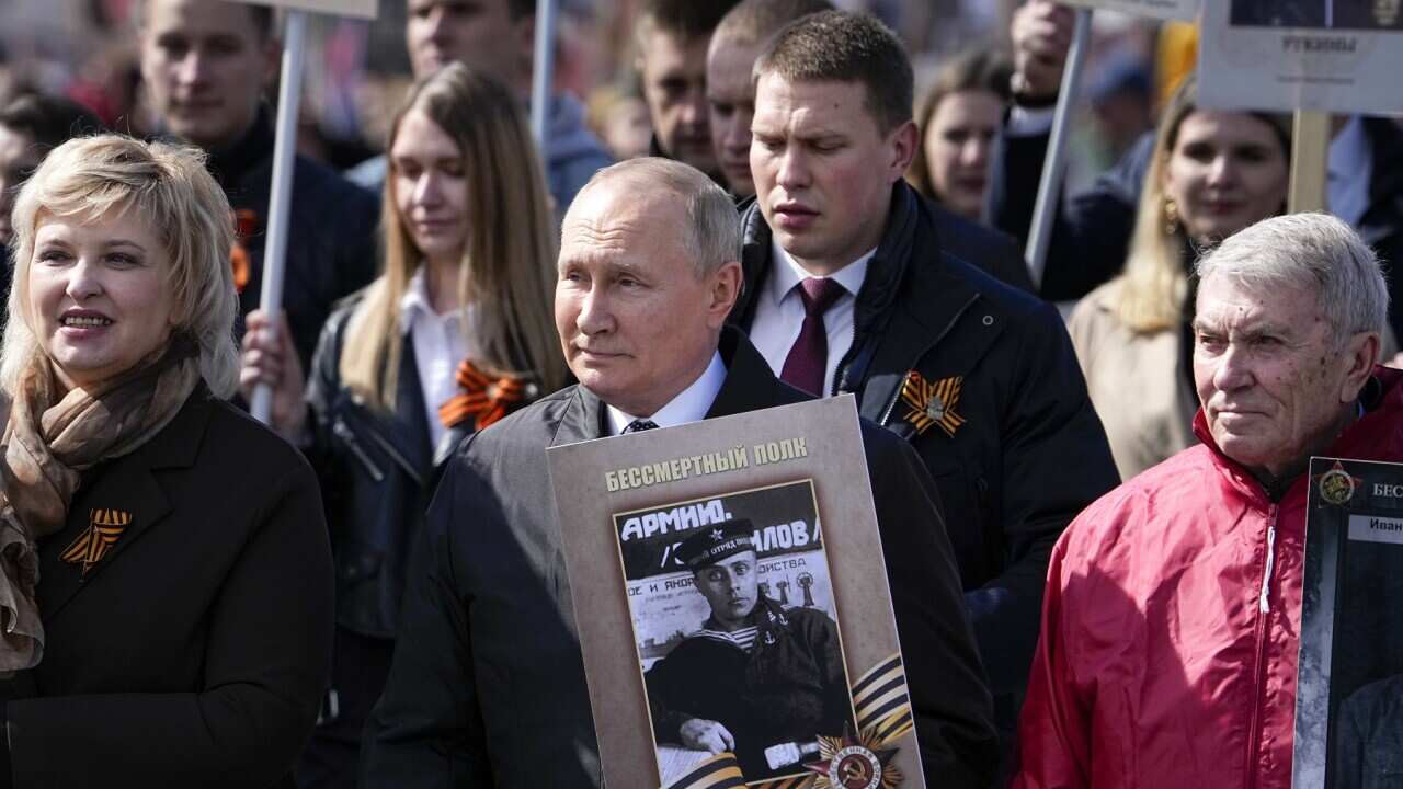 Russian President Vladimir Putin, center, attends the Immortal Regiment march through Red Square marking the 77th anniversary of the end of World War II, in Moscow, Russia, Monday, May 9, 2022. (AP Photo/Alexander Zemlianichenko)