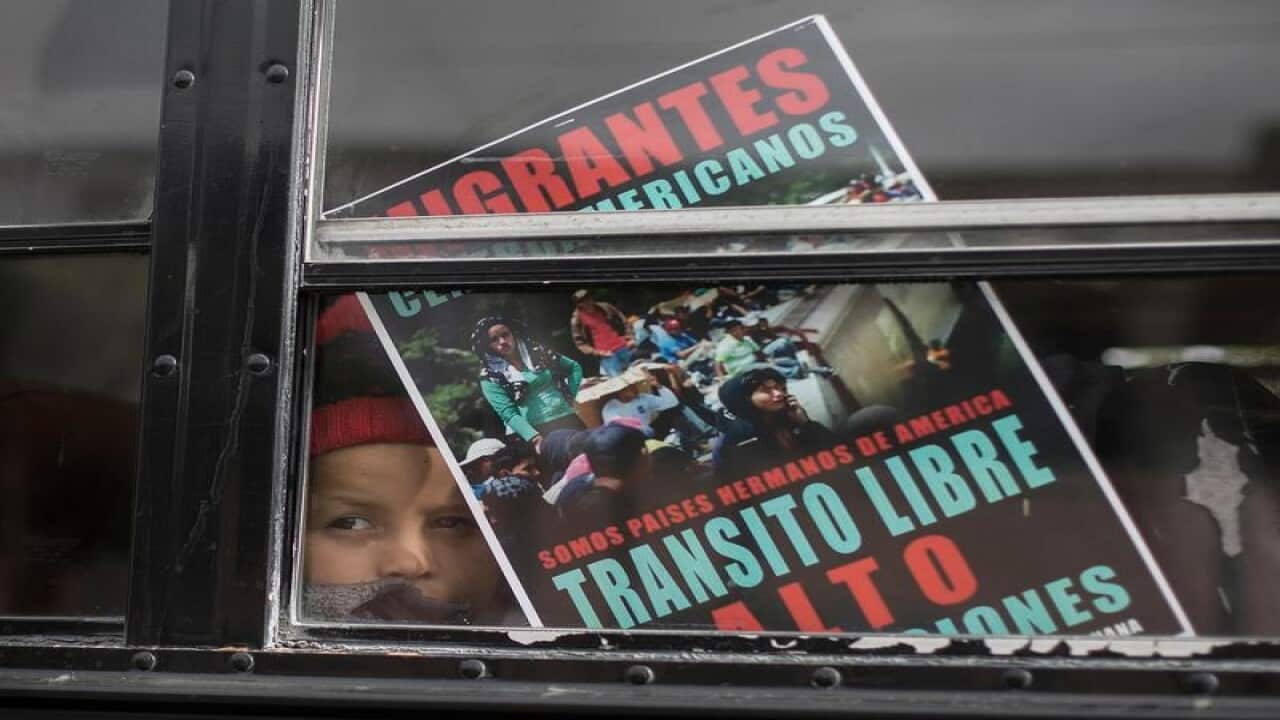 A Central American child peers out of a bus window
