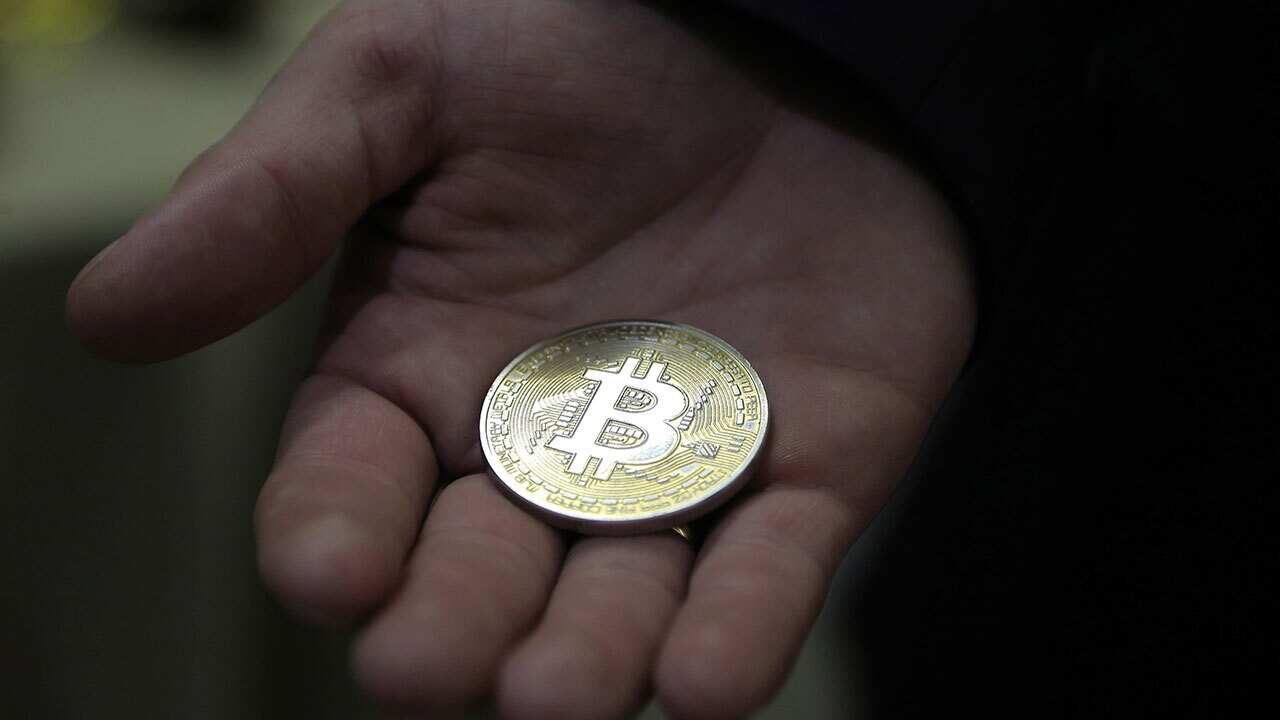 A visitor holds a Bitcoin (virtual currency) souvenir coin, during a webinar.