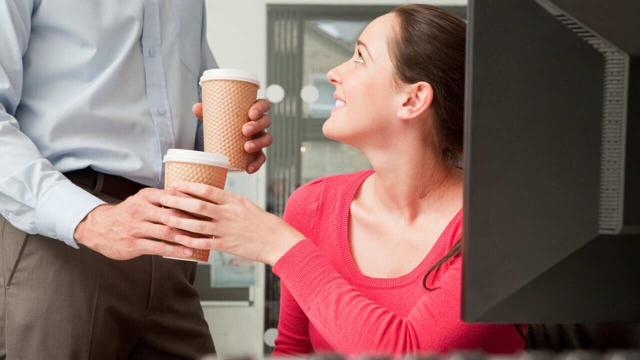 A male colleague brings a female colleague a coffee