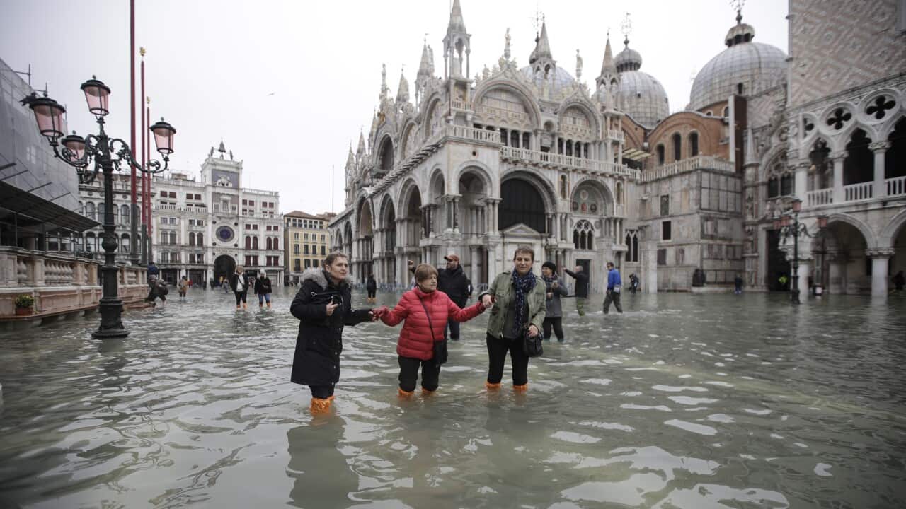 People wade through water in a flooded St. Mark's Square in Venice.