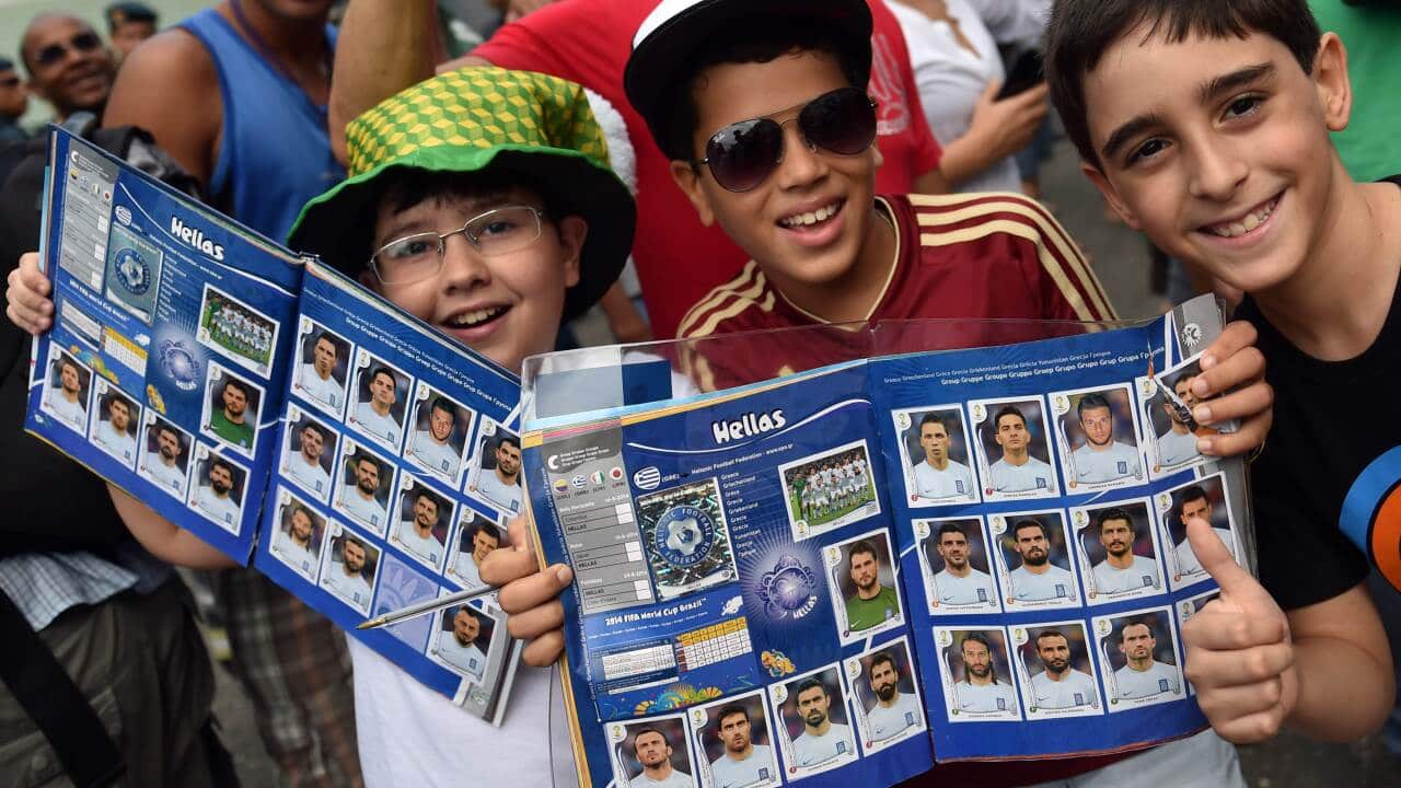 Young supporters of the Greek football team hold sticker magazines with portraits of the Greek players as the team arrive in Brazil