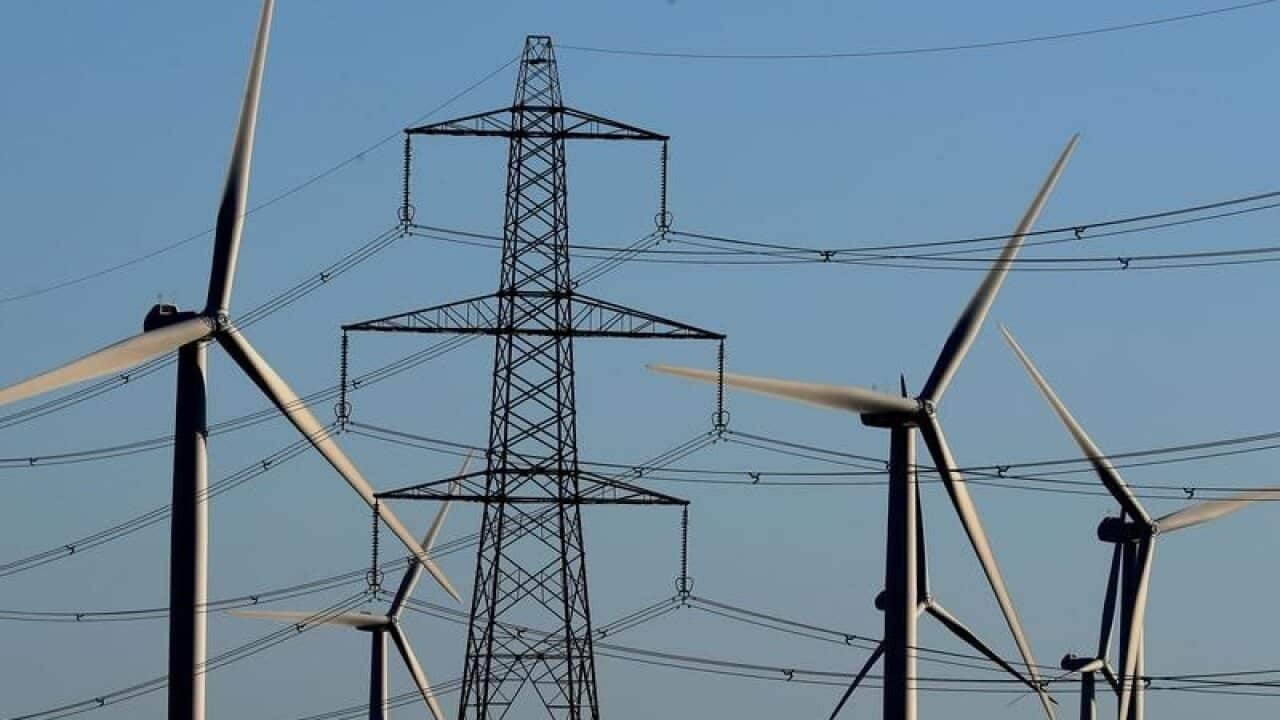 A view of a wind farm amongst electricity pylon.