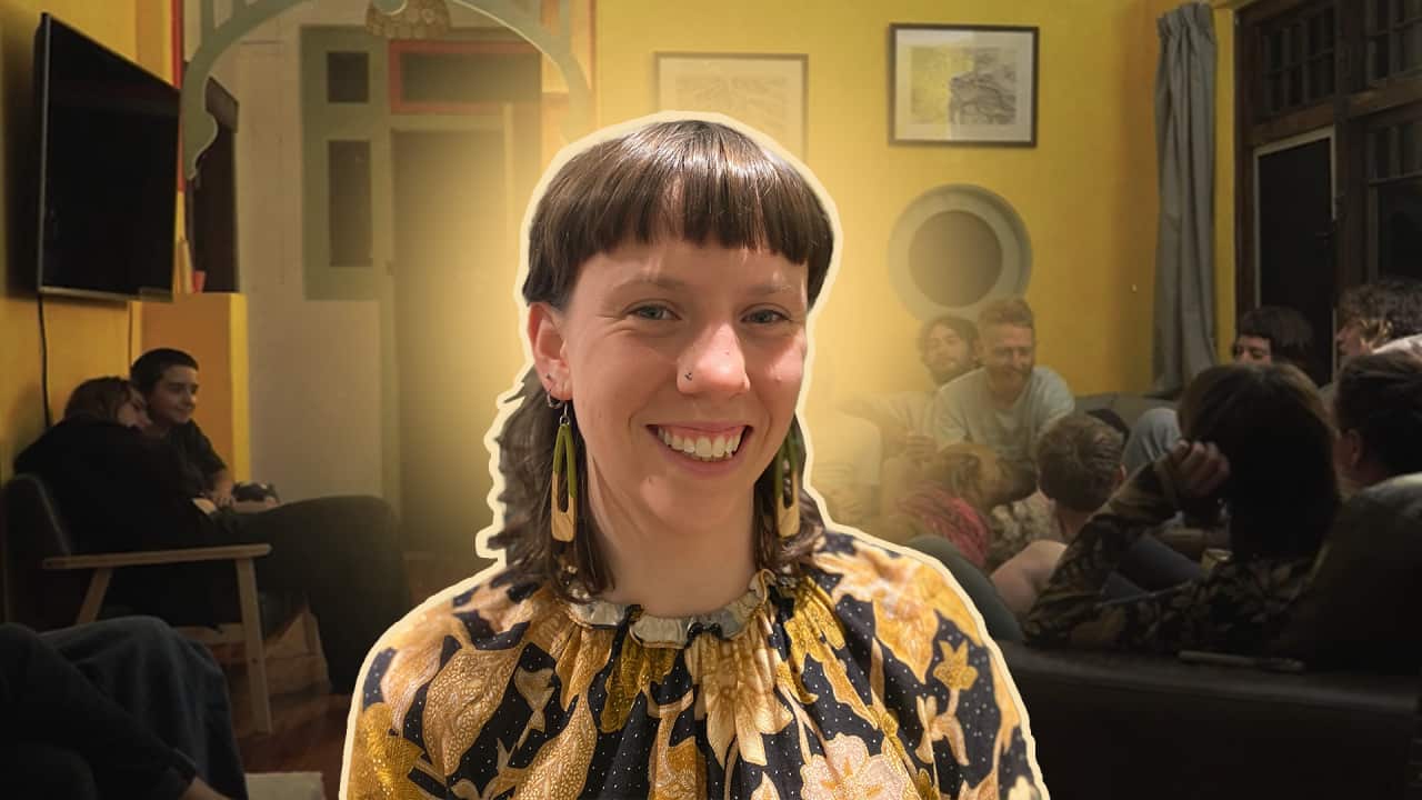 a background of a sharehouse and people sitting around and a young woman in the foreground