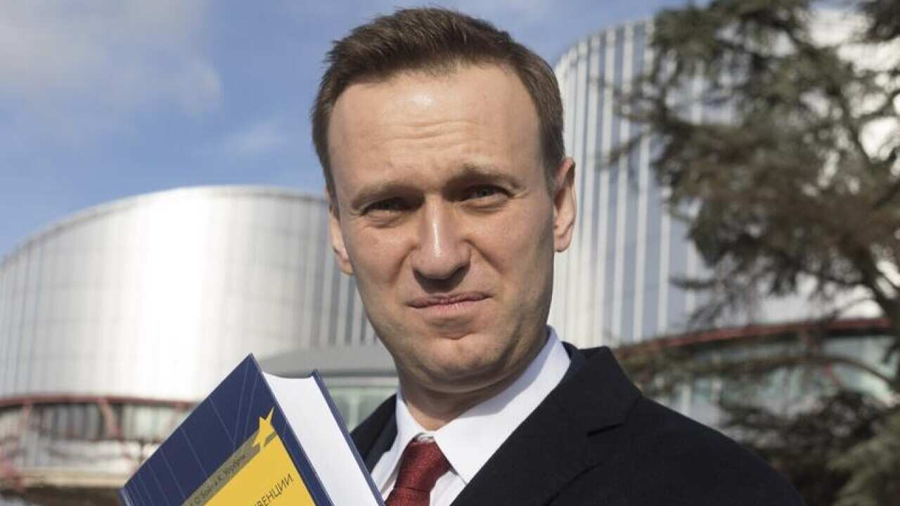 Russian opposition activist Alexei Navalny displays a book.
