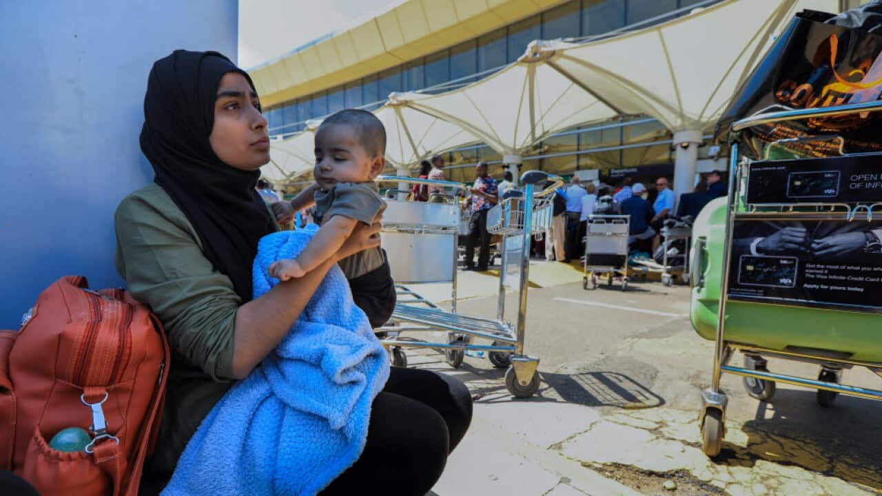 A passenger with her baby waits as she and others wait at the Jomo Kenyatta International Airport