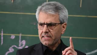 A close up of a man with grey hair in a black suit.