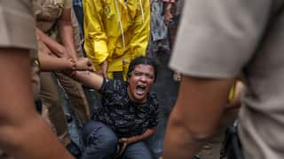 Police officers try to remove an activist during a demonstration as she screams