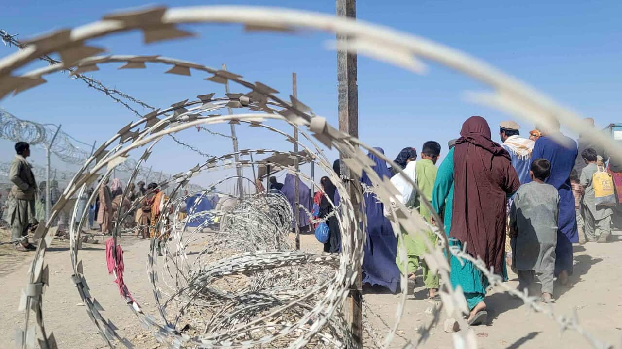 Afghan people wait to cross the border into Afghanistan, as they voluntarily depart for their homeland (AAP)