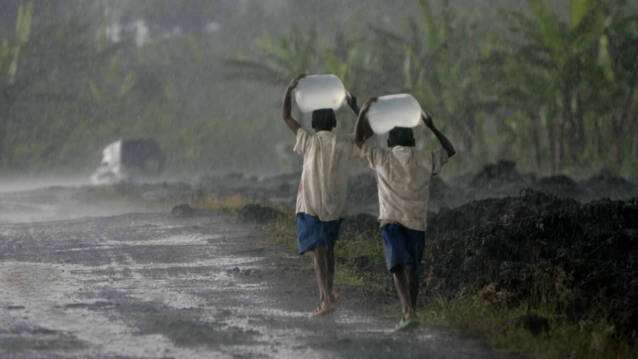 Two youths carry water on their heads in pouring rain, Thursday, Nov. 13, 2008 in Congo.