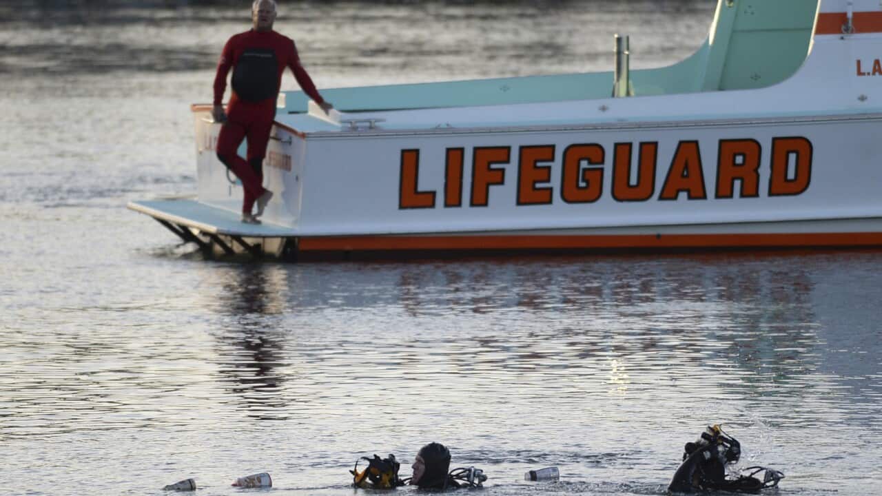 In this April 9, 2015 file photo, divers emerge from the water as debris believed to be from a car floats to the surface where a car went off a pier.