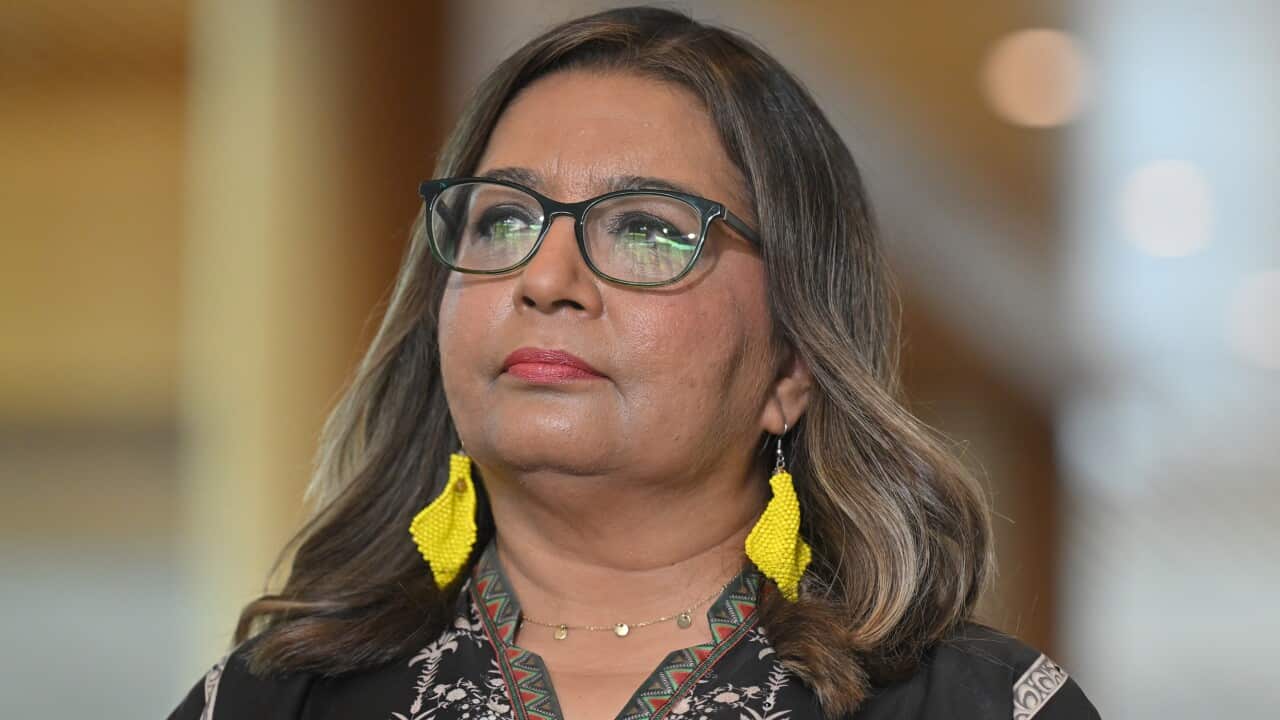 A woman with glasses and bright yellow earrings