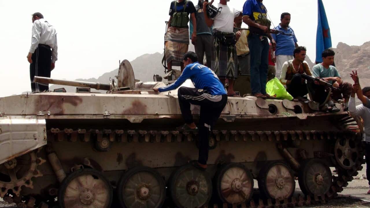 Southern Yemenis stand atop a tank in Aden