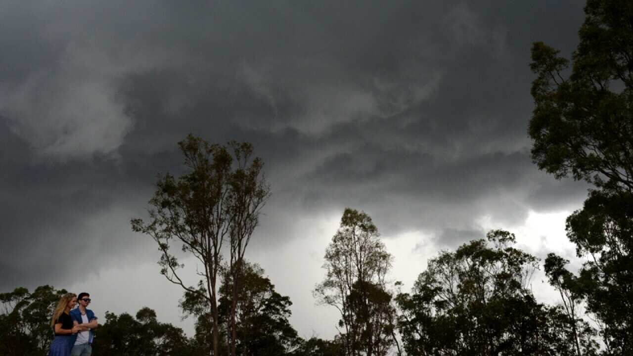 A couple watches storm clouds as they roll over Brisbane