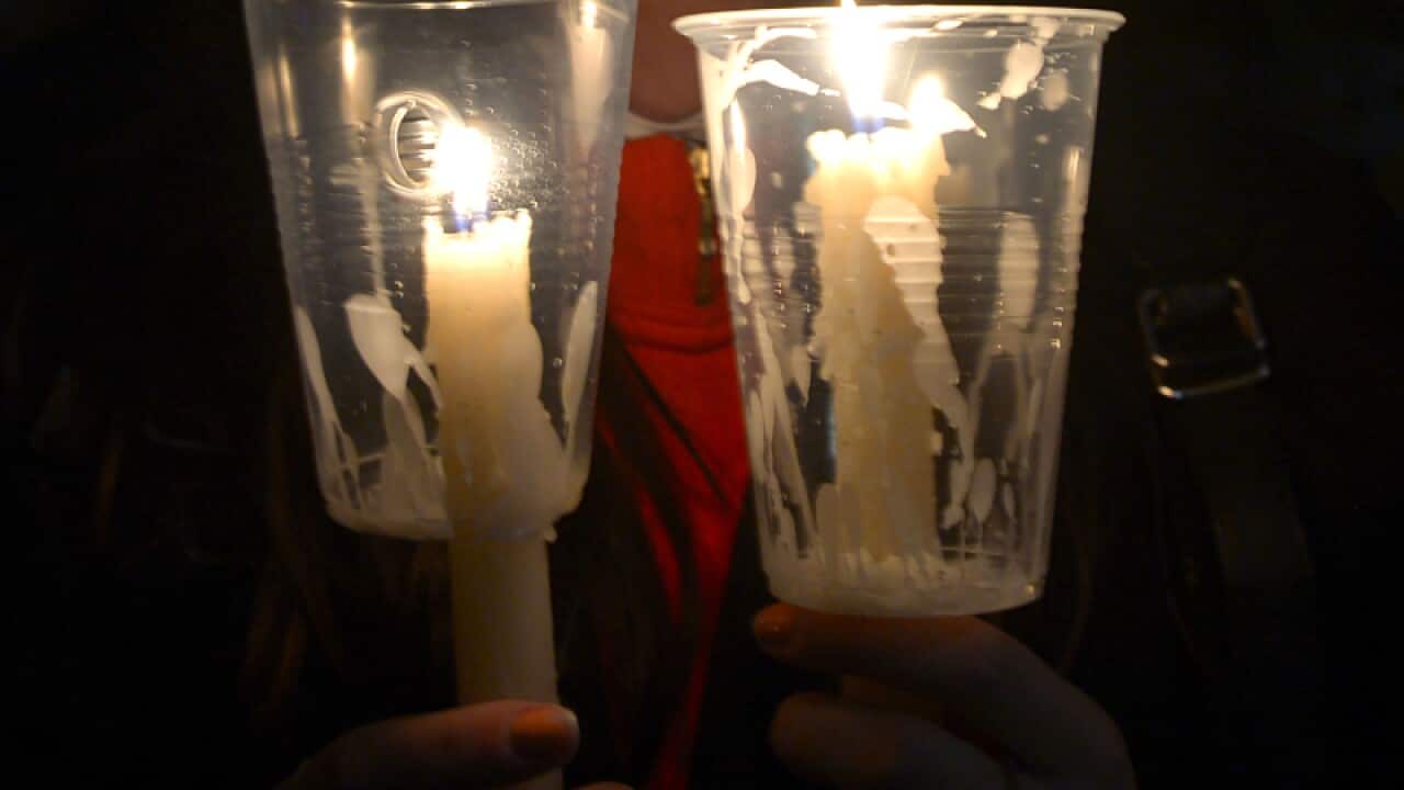 A woman holds candles during a vigil