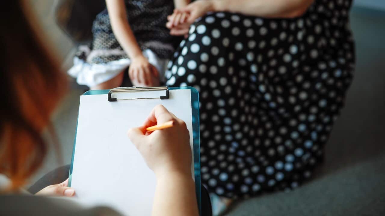 Therapeutic Connection: Psychologist Documents the Discussion with Mother and Child while Receiving Support from Mom. Touching hands, unrecognisable persons