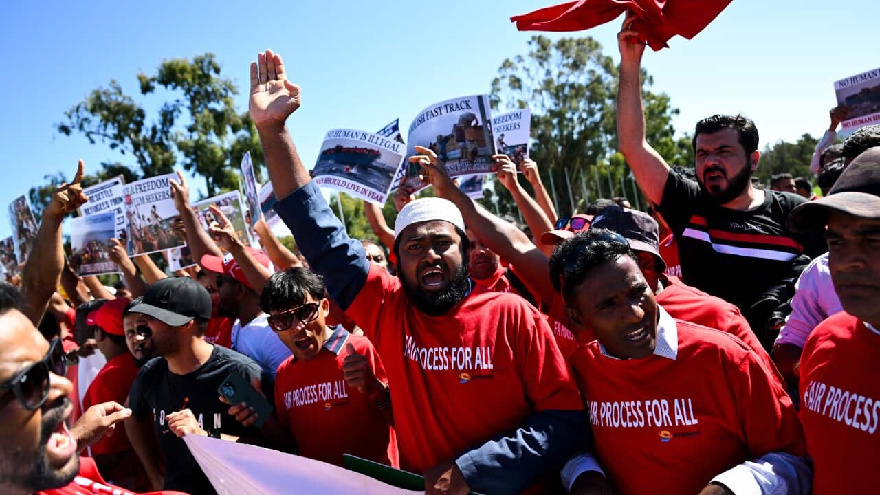 Group of protestors with signs hold their hands up.