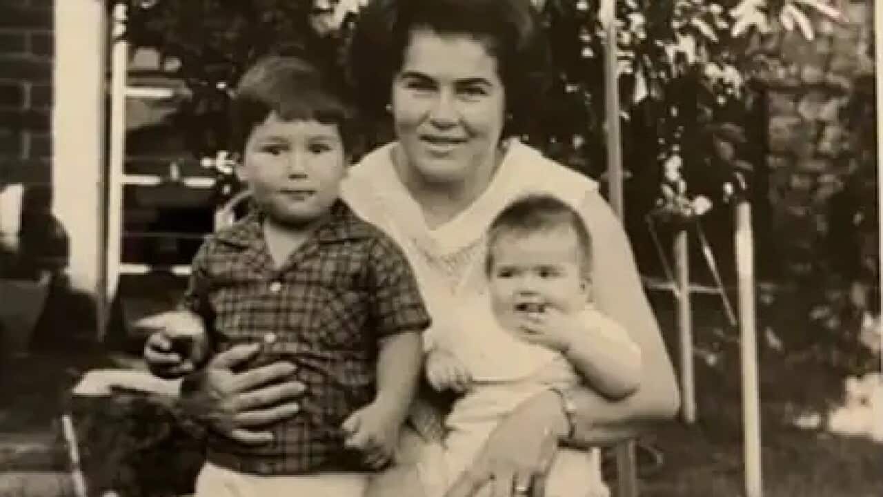 A black and white photo of a woman with two children, the girl a baby