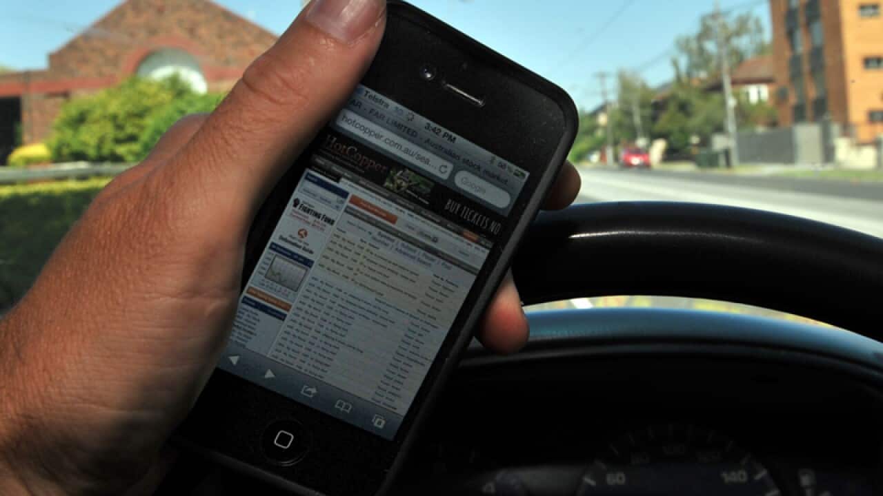 A driver holds a mobile phone whilst driving