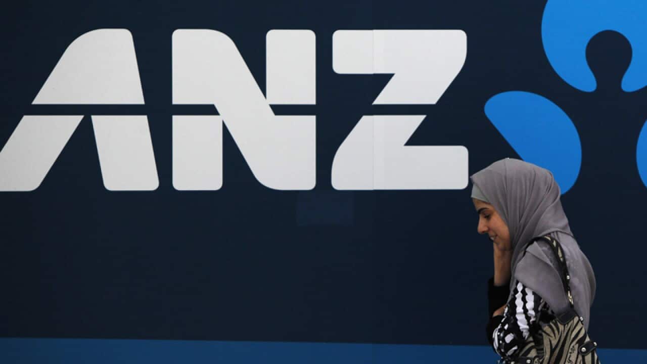 A woman walks past an ANZ bank branch