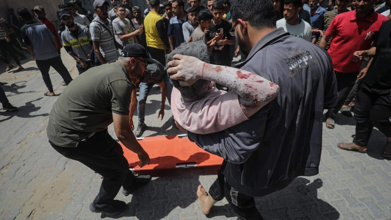 Un ferito viene trasportato da uomini palestinesi dopo un attacco aereo al campo profughi di Al Nuseirat, al centro della Striscia di Gaza.