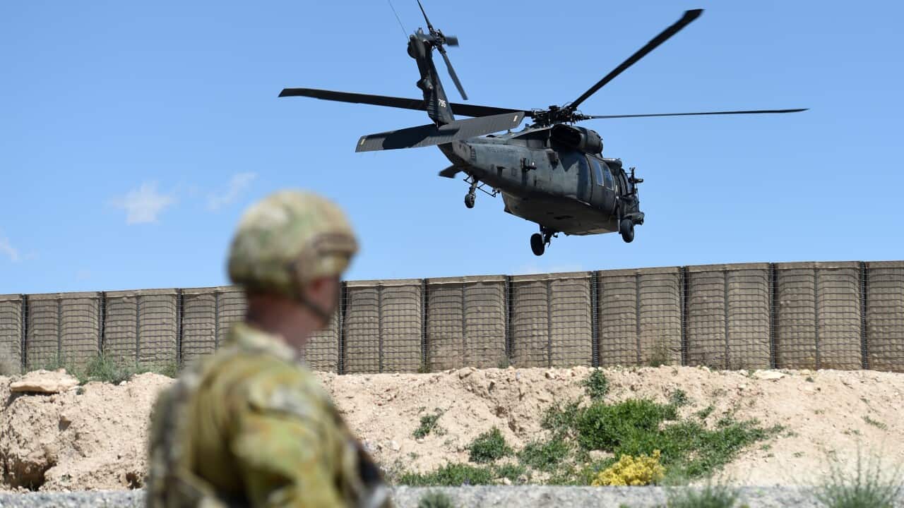 A member of the Australian Defence Force watches as a Black Hawk helicopter land at the Afghan National Army Officer Academy in Kabul, Afghanistan.