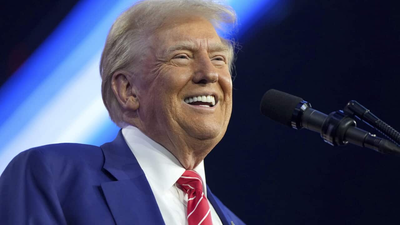 Donald Trump in a suit speaking into a microphone.