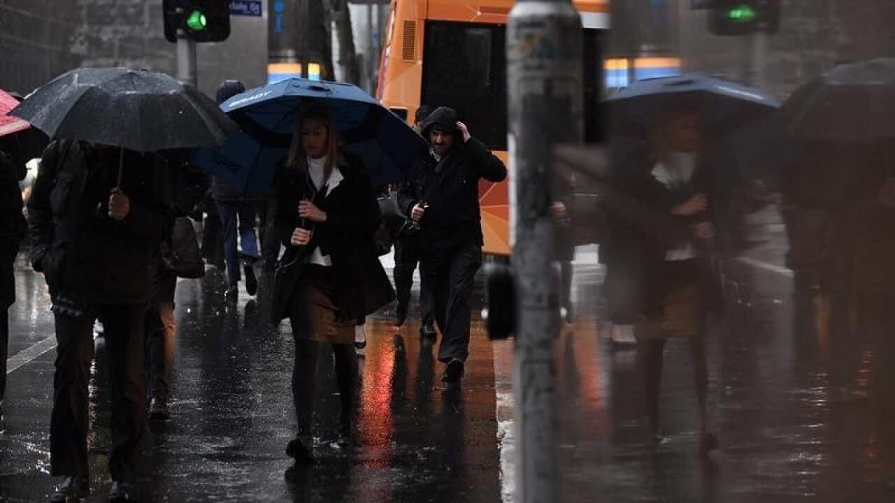 Pedestrians crossing an intersection during rain in Melbourne.