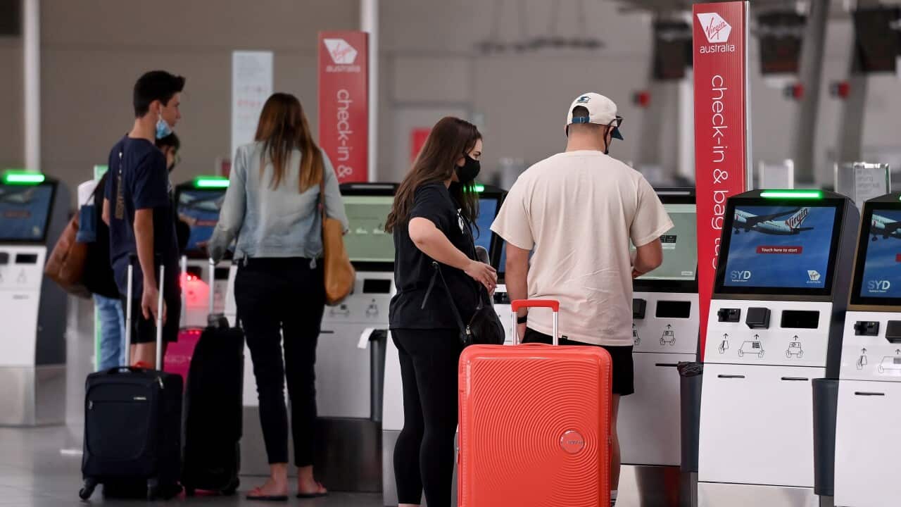 Passengers wear face masks as they check in at the Virgin Australian departures terminal at Sydney