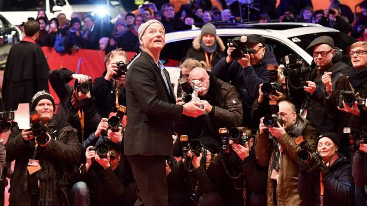 Photographers take pictures of Hollywood star Bill Murray as he holds the Silver Bear award for Best Director received on behalf of US director Wes Anderson.