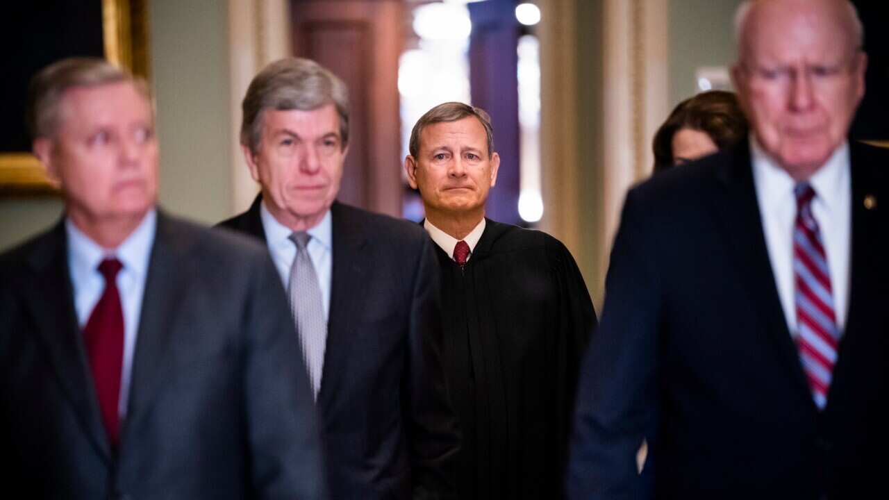Presiding officer Supreme Court Chief Justice John Roberts (c) is escorted into the Senate chamber