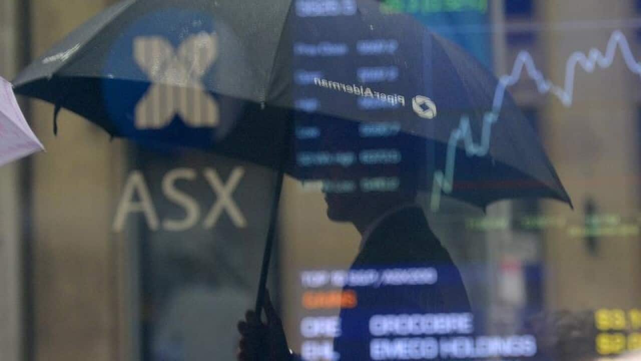 Pedestrians are seen reflected on the ASX trading board.