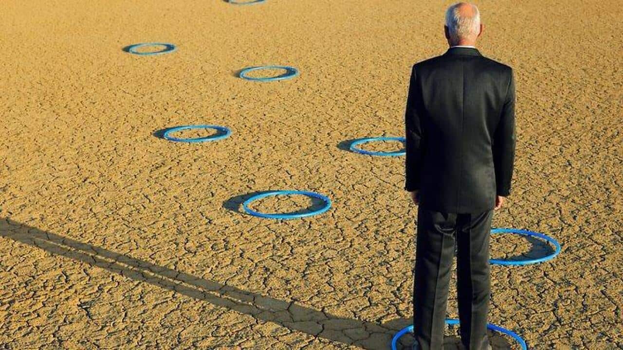 Businessman standing in hoops in desert back view full length