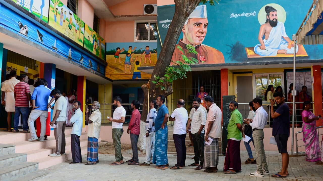Villager voters show their voter slips as they stand in a queue to cast their votes at a polling station