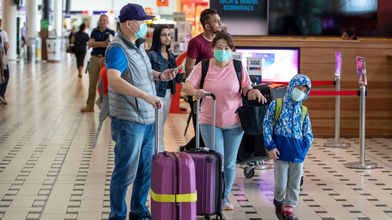 People wearing protective face masks to protect themselves from Coronavirus are seen at Brisbane International Airport