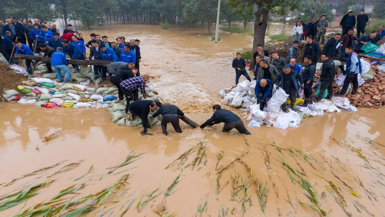 people in flood waters putting sandbacks down