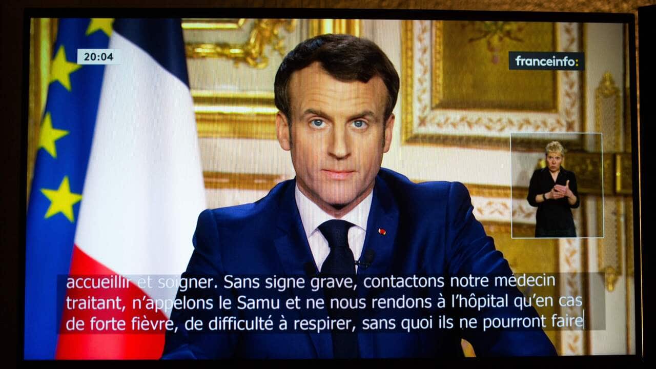 French President Emmanuel Macron is seen on a television screen as he speaks during a televised address to the nation on the outbreak of COVID-19.