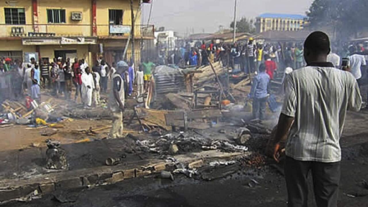 Nigerians survey the scene of a bomb blast in the city of Kaduna