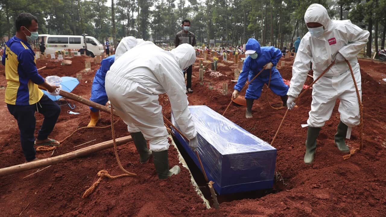 Workers in protective suits carry a coffin containing the body of a COVID-19 victim for a burial at a cemetery in Bogor, West Java, Indonesia, on 14 July, 2021.