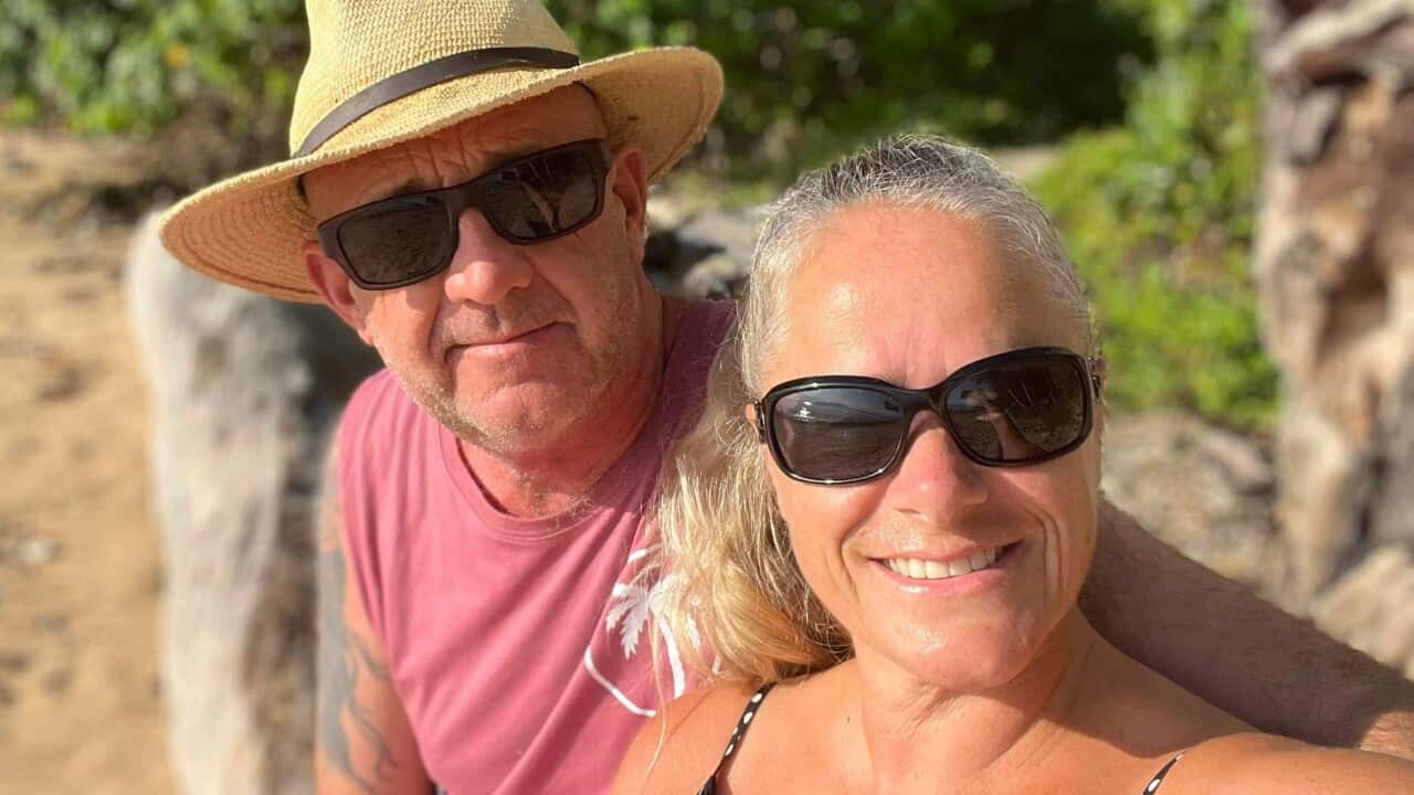 A man and a woman pose for a photo together outside