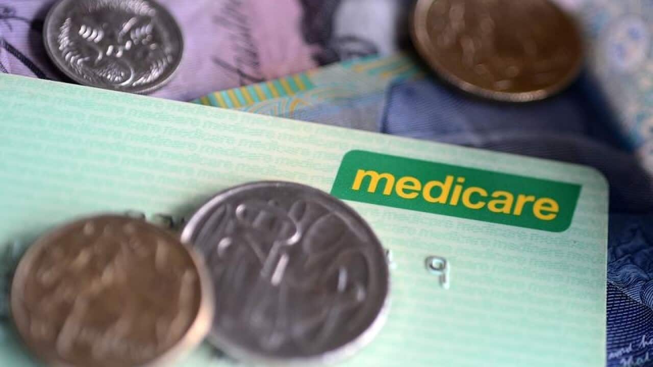 Bank notes and coins are seen with a Medicare Card.